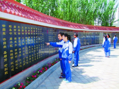 酒泉市金塔县第二中学的学生利用课余时间在文化墙前学习(图)