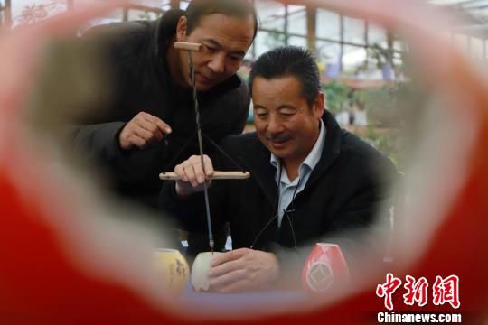 图为何文华用手工皮钻在瓷器底部打眼。 吴希会 摄 图为何文华用手工皮钻在瓷器底部打眼。 吴希会 摄