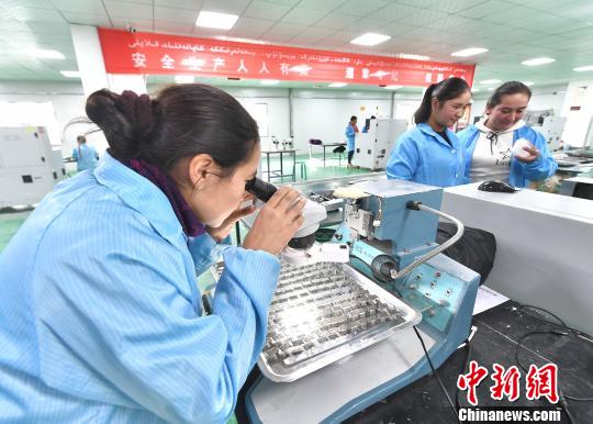 12月初，新疆喀什深圳产业园，曼古丽·阿卜杜热合曼(左)、阿依努尔·阿卜杜热合曼(中)和帕提玛·阿卜杜热依木阿(右)，三姐妹同在喀什广泓能源科技有限公司LED电子产品加工车间里工作。据介绍，该公司为员工免费提供技能培训、国家通用语言培训、舞蹈培训等，让她们适应工作的同时，还丰富她们的文化生活。公司还提供免费的工作餐，若有小孩还可免费在园区幼儿园就读。　刘新 摄