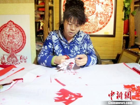 图为敦煌剪纸传承人何克风在月牙泉小镇的剪纸店里认真创作。(资料图) 田明君 摄 图为敦煌剪纸传承人何克风在月牙泉小镇的剪纸店里认真创作。(资料图) 田明君 摄