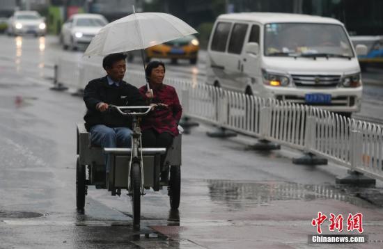 资料图：民众在雨中出行。<a target='_blank'  data-cke-saved-href='http://www.chinanews.com/' href='http://www.chinanews.com/'><p  align=