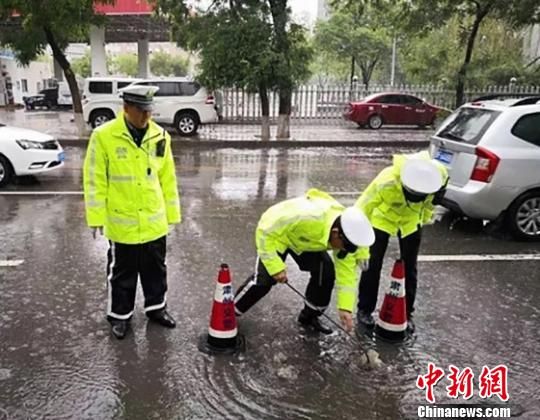 图为甘肃酒泉市交警疏通下水。 李健 摄 图为甘肃酒泉市交警疏通下水。 李健 摄