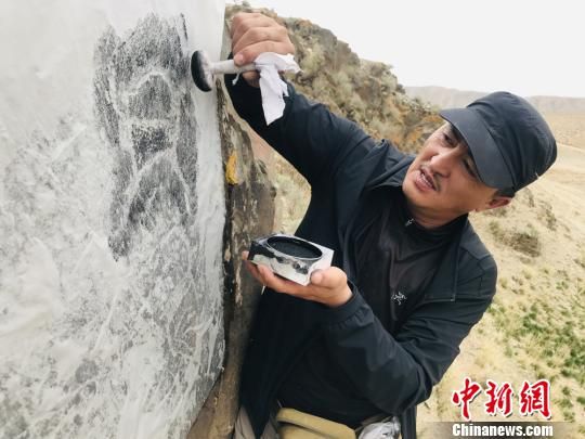 图为杜成峰按照岩画线条走向用拓包开始描边。 朵丹 摄 图为杜成峰按照岩画线条走向用拓包开始描边。 朵丹 摄
