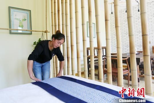 图为八月上旬,杜喜梅正在整理民宿床铺,准备迎接新客人入住。 高展 摄 图为八月上旬,杜喜梅正在整理民宿床铺,准备迎接新客人入住。 高展 摄