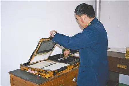 图为肖雄忠使用老式油印机印刷裁判文书.资料图片