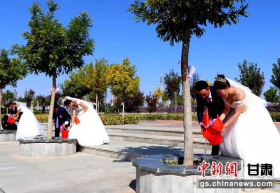 图为新人将心愿心语卡用红绳系在各自认领的爱情见证树上,共同为树木浇水。 图为新人将心愿心语卡用红绳系在各自认领的爱情见证树上,共同为树木浇水。