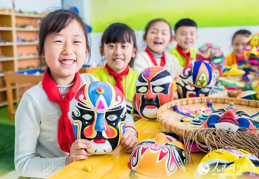 呼和浩特市玉泉区通顺街小学学生在展示绘制的戏剧脸谱作品。