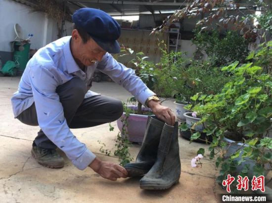 图为元古堆村民李有录翻出“压箱底”的旧雨靴，鞋底已弯曲变形。　张婧 摄