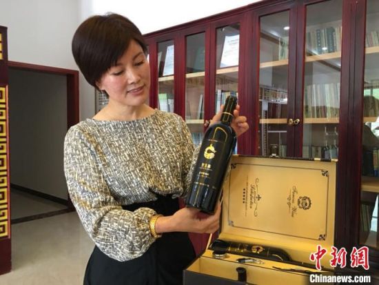  图为王玉兰向记者展示企业研发的党参葡萄酒。　张婧 摄