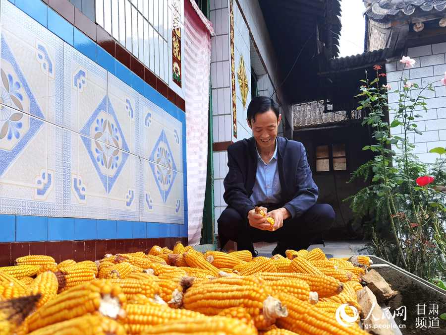 没有了繁琐小事，刘成平悠闲地剥着玉米。（高翔 摄）