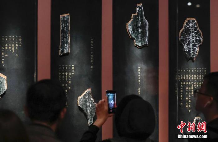 资料图:10月22日,“证古泽今——甲骨文文化展”在北京中国国家博物馆开幕。展览通过近190件甲骨、青铜、玉石、书籍实物构成的叙事链条,讲述甲骨发现与发掘的惊世过往,重温甲骨文背后的商周文明,致敬相关学者们的卓越成就。这是国家博物馆第一次举办以甲骨文为内容的文化展,也是国家博物馆馆藏甲骨的第一次大规模展示。图为甲骨碎片放大模型及译文注释吸引观众。<a target='_blank' data-cke-saved-href='http://www.chinanews.com/' href='http://www.chinanews.com/'>中新社</a>记者 贾天勇 摄 点击进入下一页