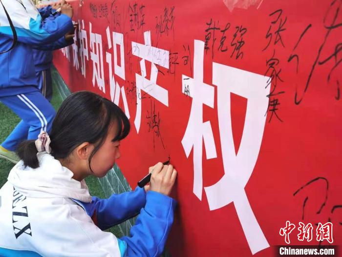 图为4月20日，学生在知识产权横幅留言签名。　史静静 摄