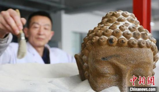 在甘肃伯骊江3D打印科技有限公司内,56岁的“玩”沙人潘炳庆清理由沙子打印佛像模型。(资料图) 高展 摄 在甘肃伯骊江3D打印科技有限公司内,56岁的“玩”沙人潘炳庆清理由沙子打印佛像模型。(资料图) 高展 摄