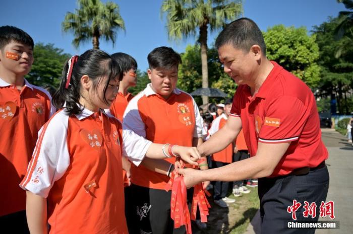 资料图:广西华侨实验高中的教师为高三学子系上红丝带,盼望学子高考必胜。 俞靖 摄 点击进入下一页