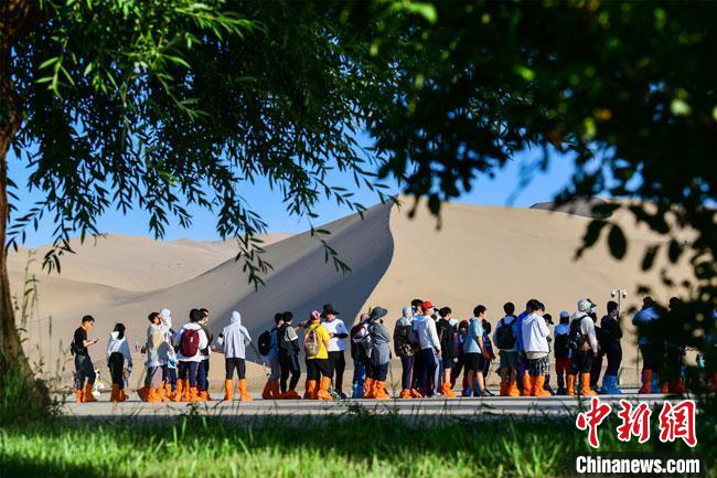 6月上旬，游人在绿树成荫的鸣沙山月牙泉景区观光游览。　王斌银 摄