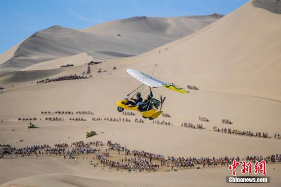图为游客乘坐滑翔机鸟瞰大漠美景。 王斌银 摄