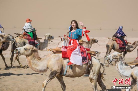 图为游客穿汉服骑骆驼畅游敦煌大漠，体验丝路风情。 王斌银 摄