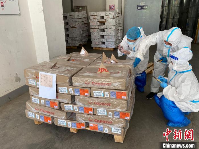 图为身穿防护服的工作人员对货品进行抽检。 徐雪 摄 图为身穿防护服的工作人员对货品进行抽检。 徐雪 摄
