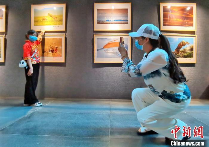 图为西宁市民铁红青为10岁的女儿和摄影作品拍照。 祁增蓓 摄 图为西宁市民铁红青为10岁的女儿和摄影作品拍照。 祁增蓓 摄