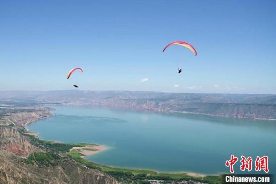 图为滑翔伞运动员在甘肃刘家峡水库上空竞技。 (资料图) 艾庆龙 摄