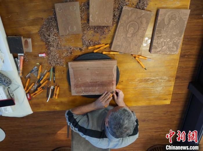 图为徐晋林正在梨木木板上雕刻敦煌壁画。　九美旦增 　摄