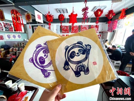 来自甘肃省庆阳市的剪纸传承人马路，凭借巧手剪出了冬奥会吉祥物“冰墩墩”。　徐雪 摄