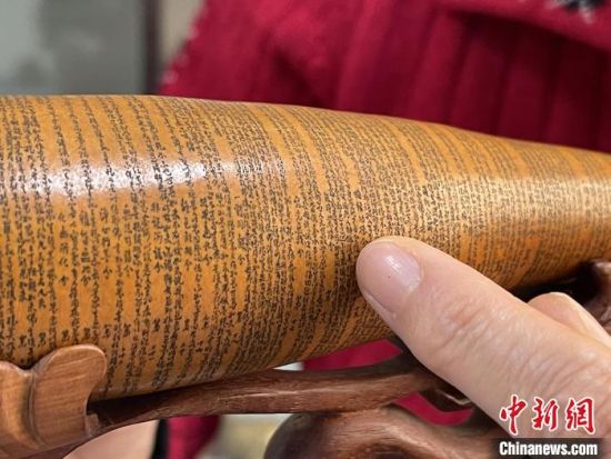图为长约二十公分的长条葫芦雕刻佛教经文作品。　张婧 摄