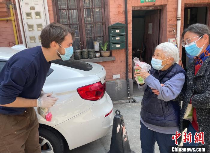 俄罗斯小伙儿Matveev(左)在给社区里的老年人派发俄罗斯甜点小礼包 受访者 供图 俄罗斯小伙儿Matveev(左)在给社区里的老年人派发俄罗斯甜点小礼包 受访者 供图
