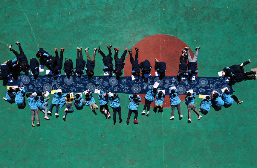 5月17日,小学生在贵州省丹寨县龙泉镇羊甲小学课后服务中学画苗族传统蜡染图案(无人机照片)。