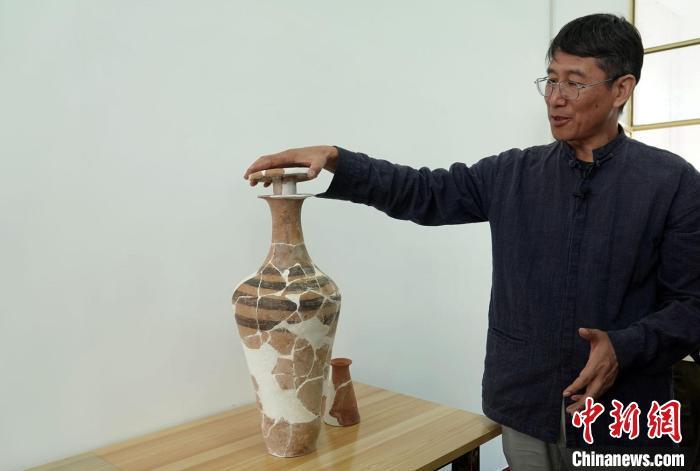 韩建业教授介绍南佐遗址发掘出土的一件独具特色彩陶器——带盖塞(防止酒类液体等挥发)的小口细颈平底瓶。　中新社记者 孙自法 摄