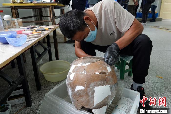 南佐遗址考古基地的整理室内，工作人员正在修复一件出土陶器。　中新社记者 孙自法 摄