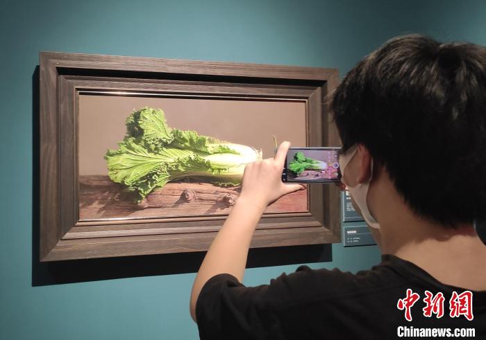 参观者拍摄写实油画《如意百财》。 邓霞 摄 参观者拍摄写实油画《如意百财》。 邓霞 摄