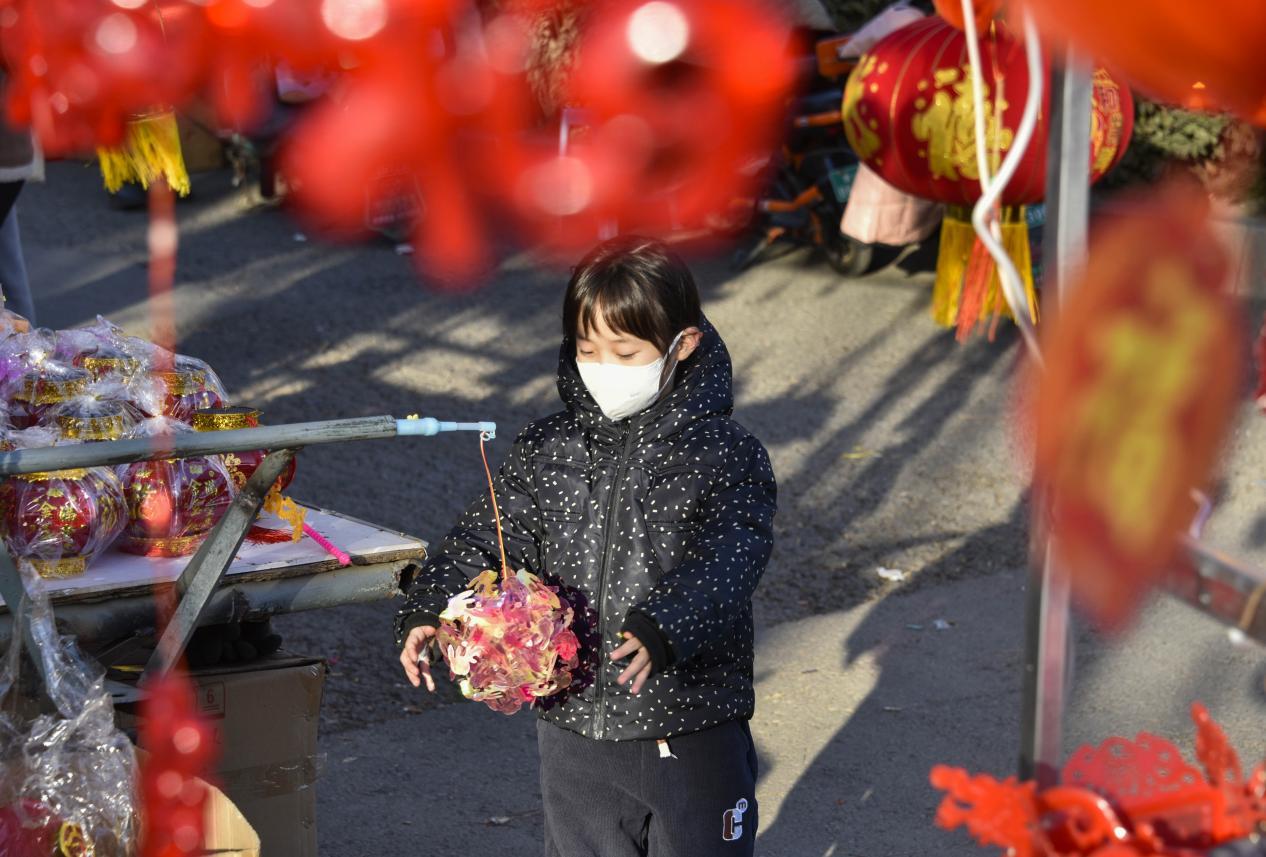 一名儿童在唐山遵化民俗集市上摆弄玩具。 张旭摄