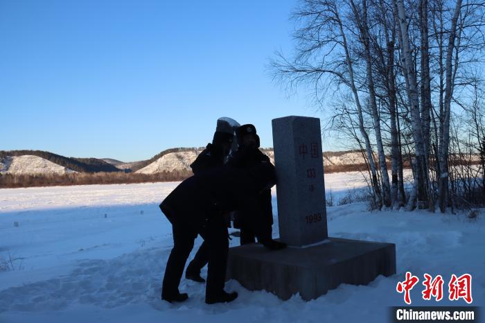 图为恩和哈达边境派出所的民警们清理界碑上的积雪。 牟东印 摄 图为恩和哈达边境派出所的民警们清理界碑上的积雪。 牟东印 摄