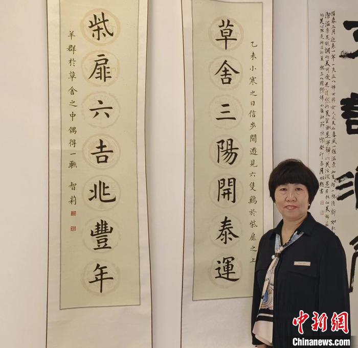 刘智莉在天津市静海区举办的“三.八国际妇女节”女书画家优秀作品展上与自己的作品合影。　受访者供图