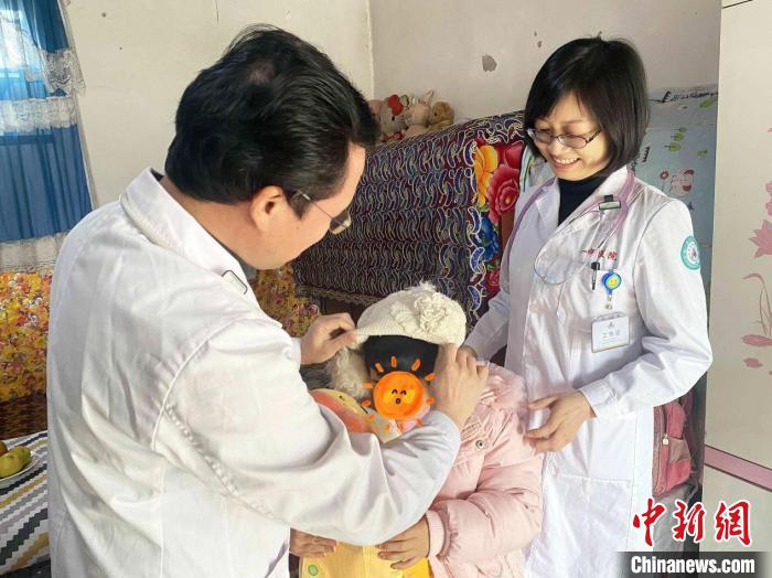 彭克荣给小古丽戴帽子。 周玲玲 摄 彭克荣给小古丽戴帽子。 周玲玲 摄