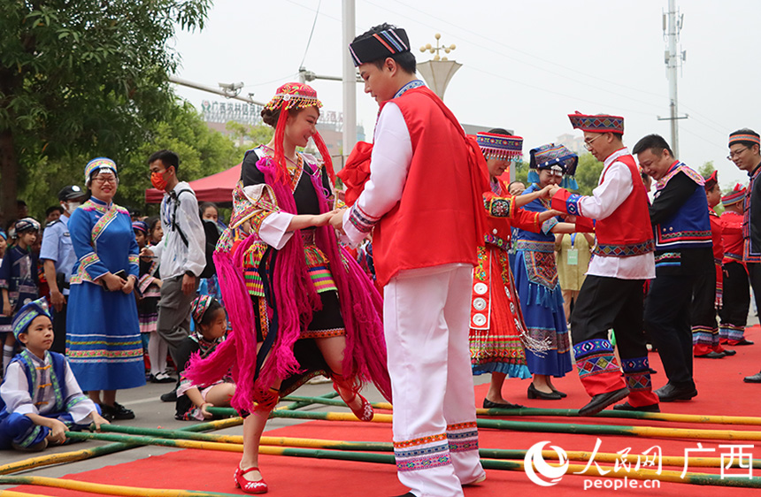 同时，场地另一头，一阵阵铿锵有力、节奏明快的响声传来，来自壮族、汉族、瑶族等不同民族的男女老少身着盛装，跳起竹竿舞。人民网记者 彭远贺摄