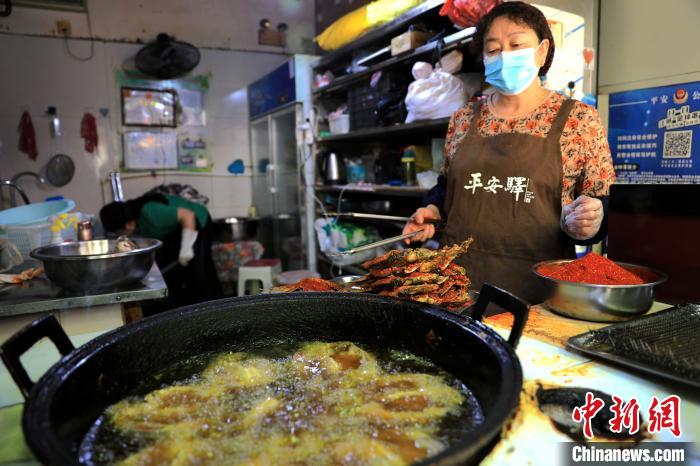 图为平安驛·河湟民俗文化体验地内的商户炸干板鱼。　薛蒂 摄