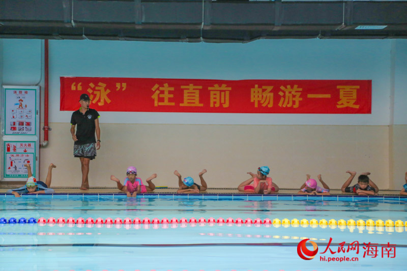 今年暑期,三亚22座泳池暑期向中小学生免费开放,在三亚市吉阳区丹州小学游泳馆内,教练正指导学生练习游泳动作。人民网 牛良玉摄