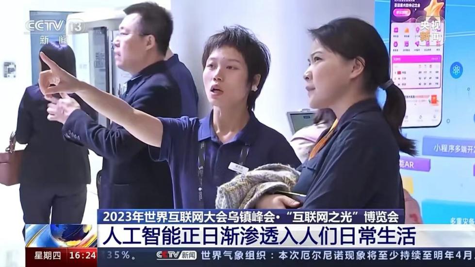 2023年世界互联网大会乌镇峰会,记者(右一)在人工智能相关展台参观采访。央视新闻截图