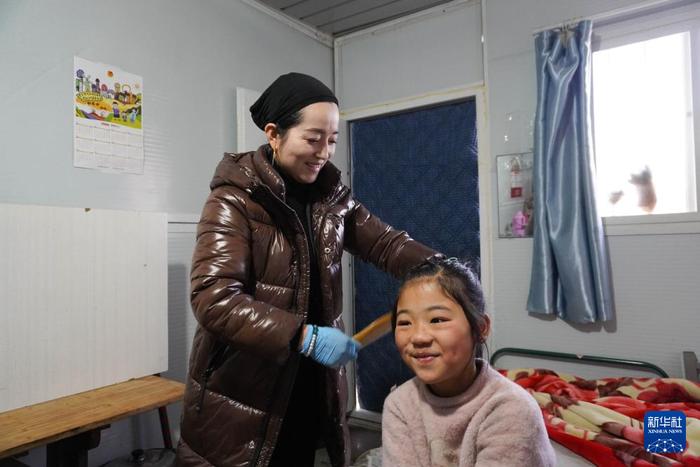 ？？1月16日，在甘肃省临夏州积石山县刘集乡阳洼村安置点的板房内，群众为孩子梳头发。新华社记者 马希平 摄
