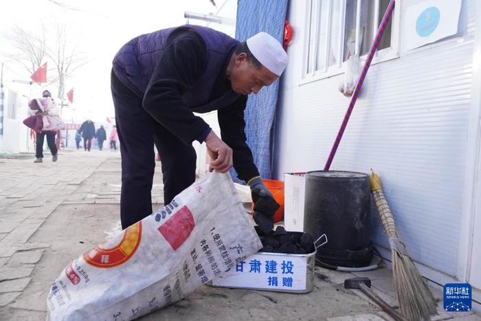 ？？1月16日，在甘肃省临夏州积石山县刘集乡阳洼村安置点的板房门口，群众捡拾煤炭准备烧火炉。新华社记者 马希平 摄