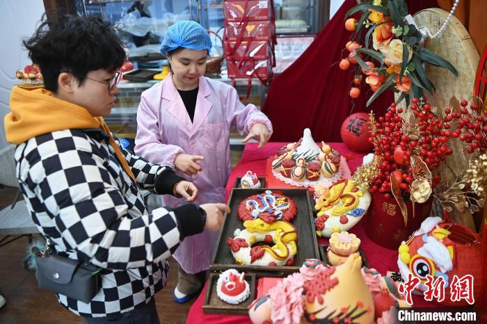 1月25日，随着春节临近，兰州一花馍店“龙”元素花馍热销。图为工作人员向顾客推荐“龙”元素花馍。九美旦增 摄</p><p>