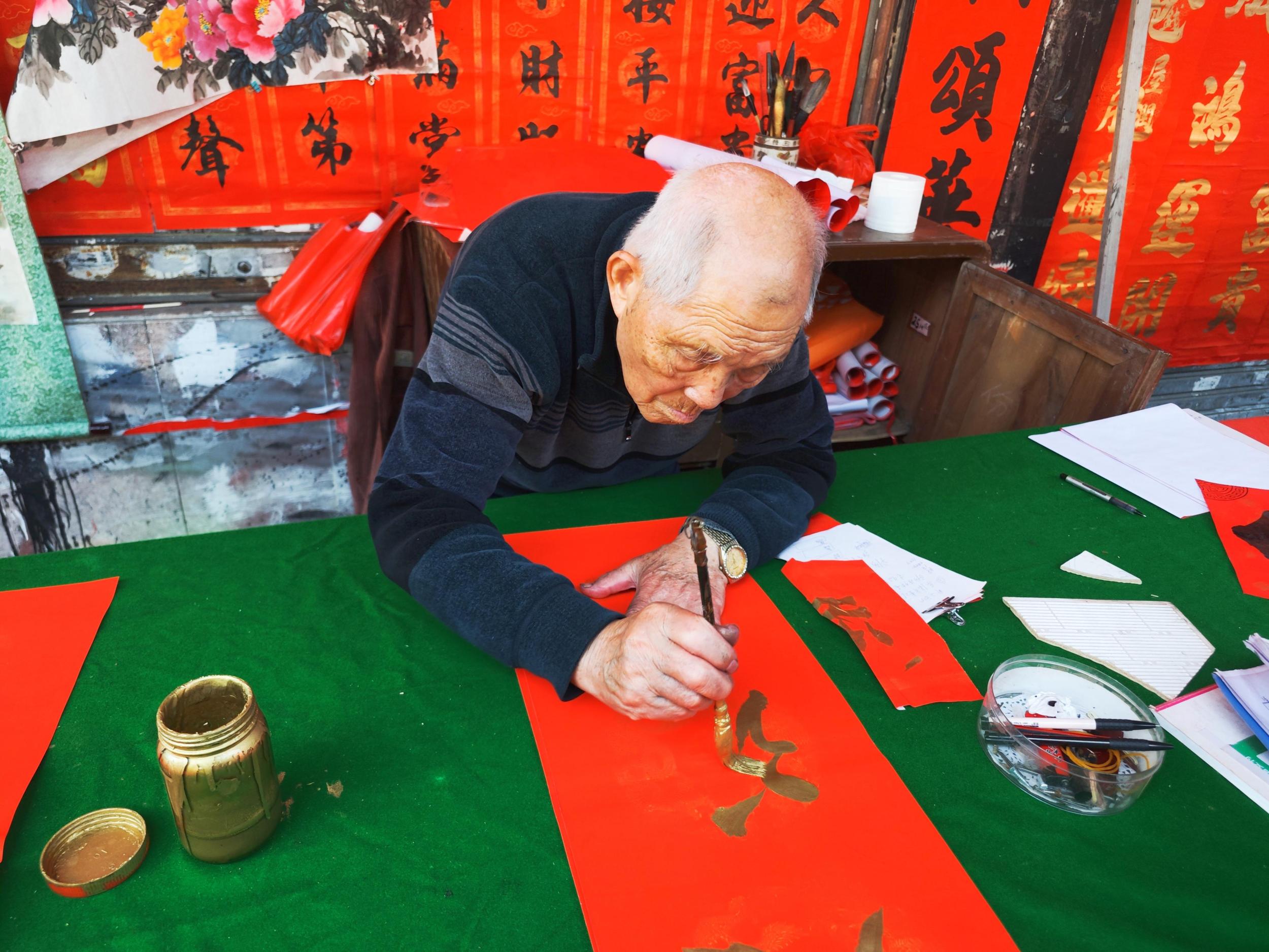快子路上，年近九旬的老师傅正在用金漆书写春联。人民网 朴馨语摄