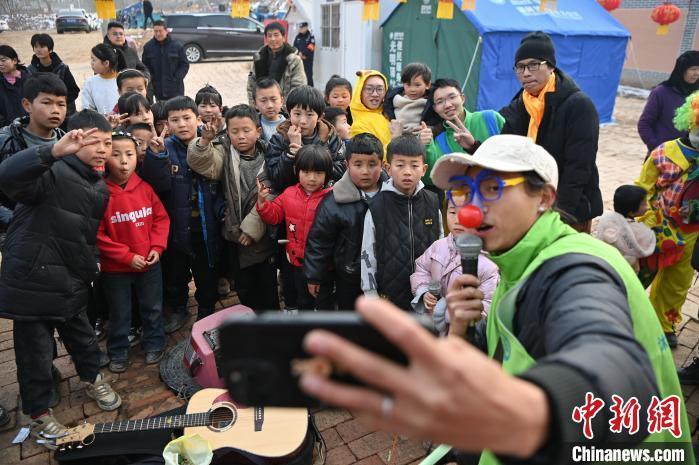 图为来自四川乐山的“流浪歌手”汤小乐和甘肃临夏州积石山县大河家镇克新民村的孩子们一起唱歌。九美旦增 摄