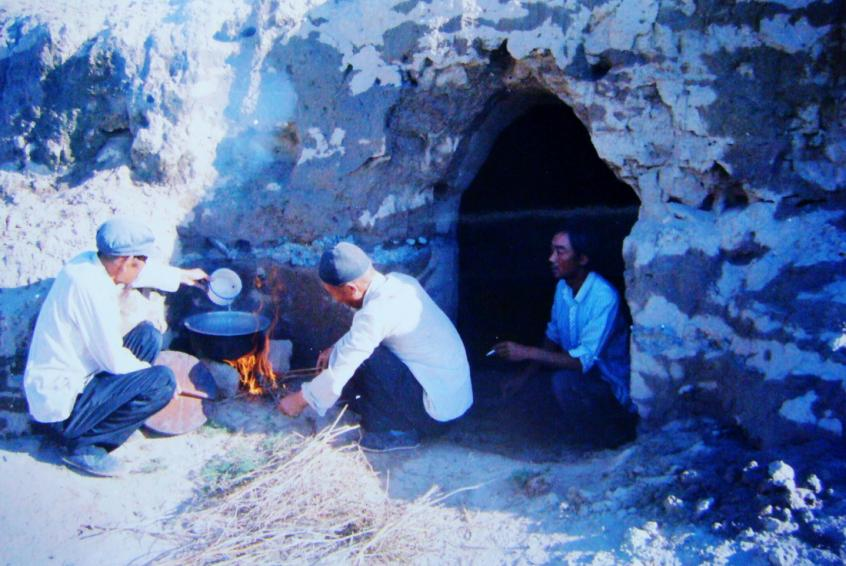 1983年,“六老汉”一代治沙人在“地窝子”生活做饭。新华社发(八步沙林场供图)