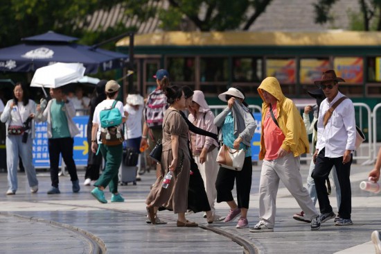 6月23日,在北京前门大街,游客穿着防晒服抵挡烈日。新华社记者 鞠焕宗 摄