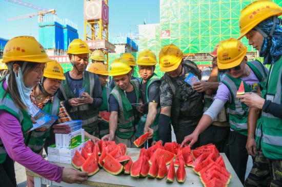 6月11日,在河北雄安新区启动区西北片区小学项目建设现场,中铁十二局工人吃西瓜解暑。新华社记者 牟宇 摄