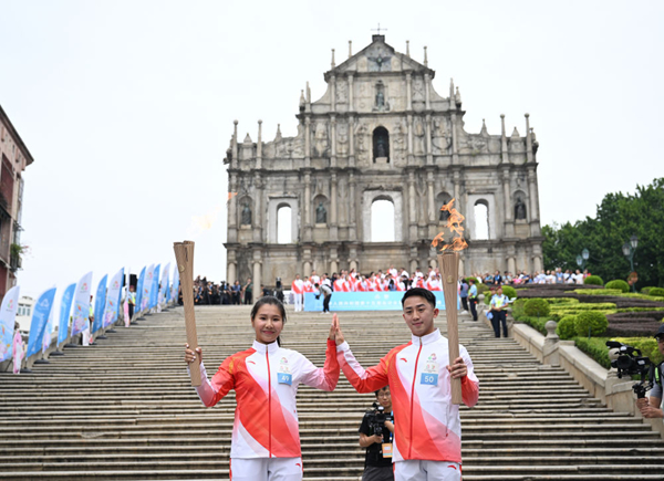 火炬手郭建恒(右)、区海欣在大三巴牌坊前传递火炬。新华社发(张金加摄)