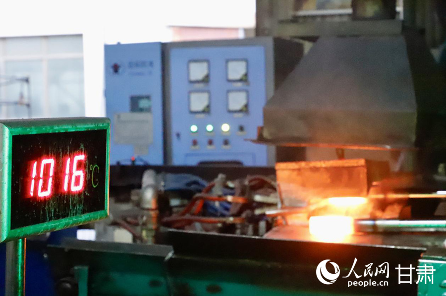 定西高强度紧固件股份有限公司智能化车床上,螺柱正经历千度高温的一体成型锻造。人民网记者 焦隆摄